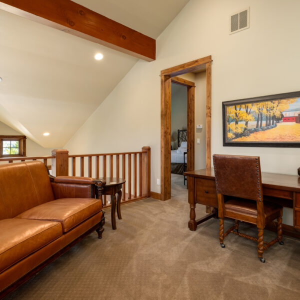 a upstairs room with a couch and a desk with a painting on the wall