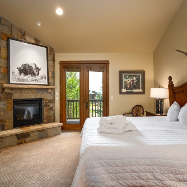 a western bedroom with a king size bed and stone fireplace