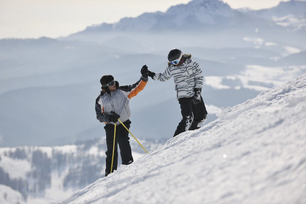 Ski instructor high fives student on ski slope