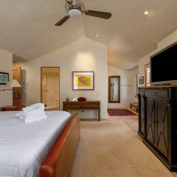 a large bedroom with a leather framed bed and a black tv stand