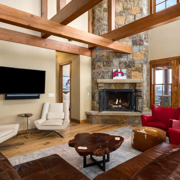 open living room with brown leather sectional and stone fireplace