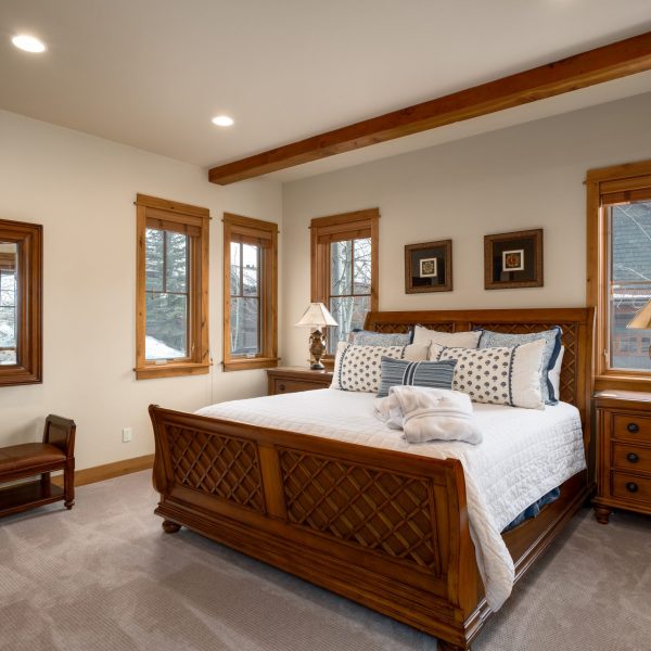 indian summer wood framed large queen bed in a bedroom with a lot of big windows